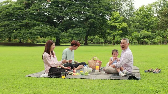 Happy mother and daughter, Happy Asian family having fun time on picnic at city nature park sunny day, outdoor activitie with daughter father, mother and grandfather