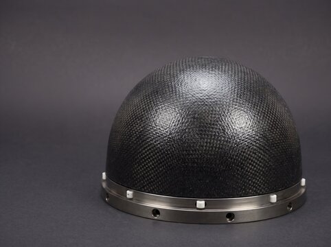 Product studio macro photograph of reinforced carbon carbon rcc aerodynamic nose cone dome displaying dense woven graphite matrix texture for atmospheric reentry thermal protection system