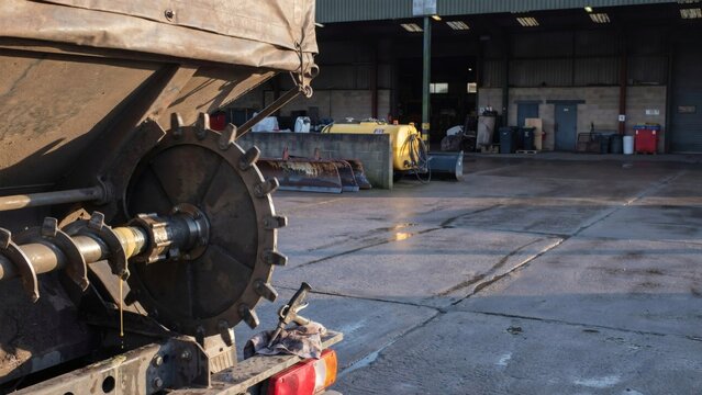 Spinner disc and auger of a gritting lorry being greased in a depot yard before winter