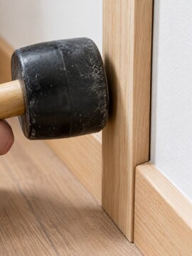 Hombre usando un mazo de goma para ajustar un marco de madera en una habitaci&oacute;n