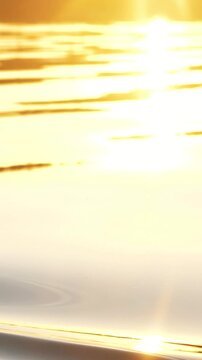 Close up of a bright orange paddle blade dipping into the reflective water during sunset, creating elegant ripples and water drops while kayaking in the golden light