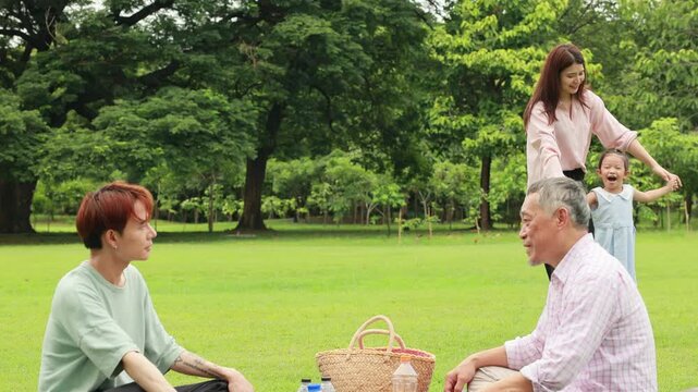 Happy mother and daughter, Happy Asian family having fun time on picnic at city nature park sunny day, outdoor activitie with daughter father, mother and grandfather