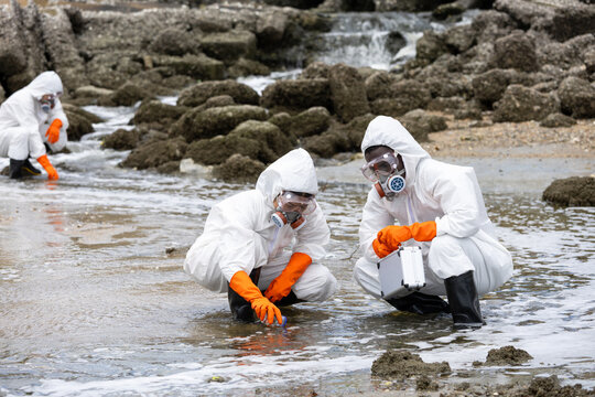 Scientists in hazmat suits collecting water samples from a polluted stream, environmental researchers inspecting water contamination outdoors, team of specialists testing water quality in nature