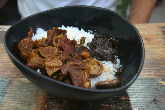 A close-up of braised beef (Ngau Lam) with chu hou paste, fermented spinach and rice, local Cantonese dish served in street side food stall (dai pai dong). Central, Hong Kong