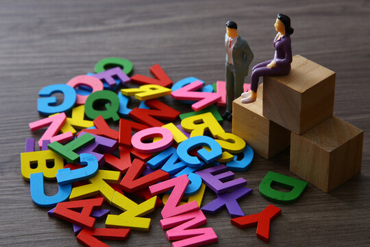 Miniature people standing next to colorful alphabet letters