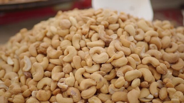 Close up cinematic view of roasted cashew nuts pile at local market stall with slow camera motion