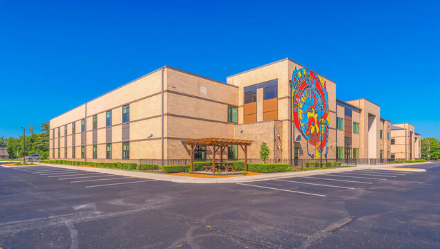 Modern brick building with vibrant mural and outdoor seating area