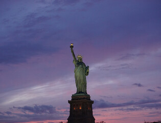 Statue of Liberty against a purple sunset sky, New York Harbor © Phumipat
