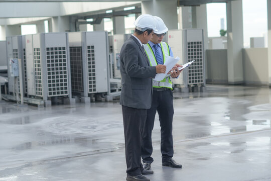 Engineer inspector rooftop air conditioning maintenance safety hardhat clipboard checklist male professional review checklist near ventilation unit, planning equipment inspection commercial roof