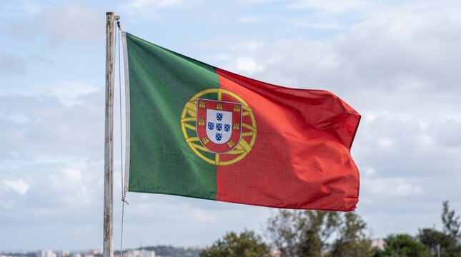 Waving flag of portugal against a cloudy sky representing national pride