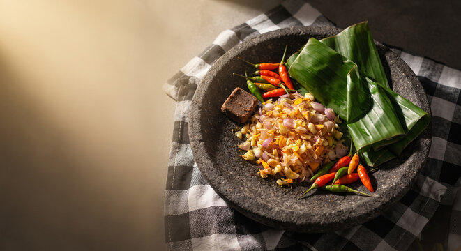 Traditional Indonesian sambal matah with fresh chilies in a stone mortar