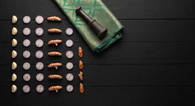Flat lay of neatly arranged garlic, shallot, and turmeric with a vintage mortar