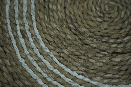 Circular woven jute rug texture with white stitched detail close up
