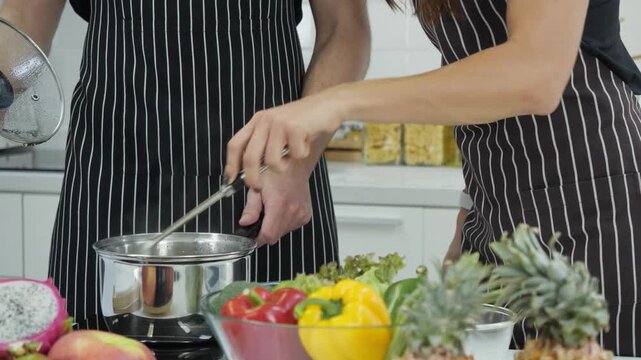 Two women Cooking, taste and woman in kitchen for lunch, food and chef at counter with fresh recipe. Diet, wellness and girl at stove for meal prep, nutrition and eating vegetables from pan. cuisine
