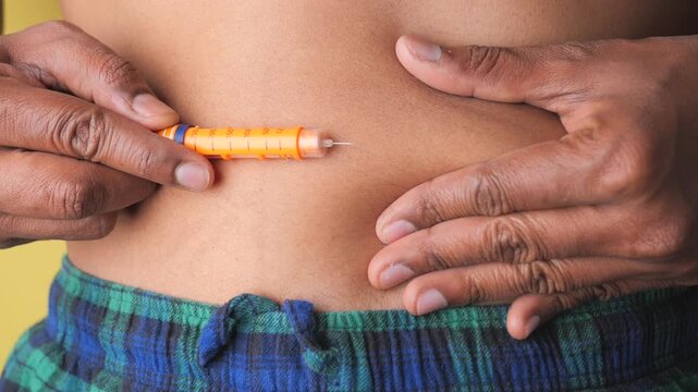 Man injecting insulin pen into stomach for diabetes treatment and blood sugar management