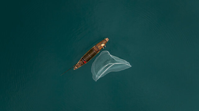 Aerial View of Fisherman Casting Net from Wooden Boat on Xiaodongjiang River