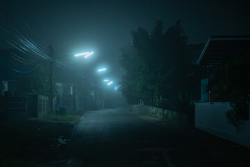 Naklejka premium Misty empty neighborhood street illuminated by cold neon streetlights at dark quiet night.
