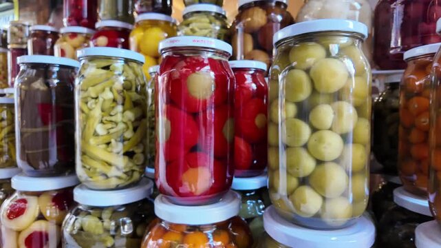 A vibrant assortment of colorful pickled vegetables and fruits in glass jars, showcasing homemade preserves for sale