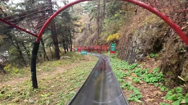 First person perspective view of tourist sliding down on toboggan from Mutianyu section of China Great Wall