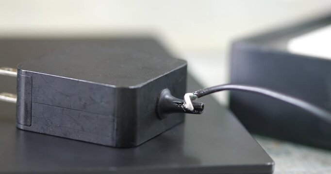 Close up of damaged power adapter with broken and frayed cable wire