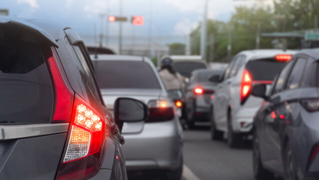 Rear side of grey car with turn on brake light on asphalt road. Vehicles wait in heavy traffic congestion on an urban street with brake lights glowing bright red. Cars were lined up densely.