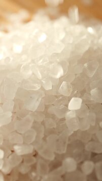 Extreme close up of white sea salt crystals falling onto pile with shallow depth of field