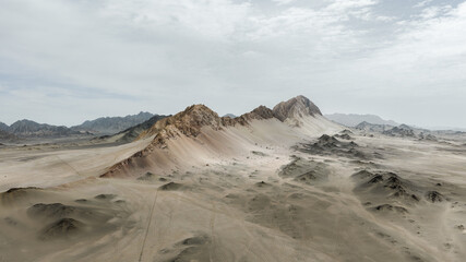 Aerial View of Rocky Desert Mountains and Sandy Terrain Under Cloudy Sky © HoangNgoc