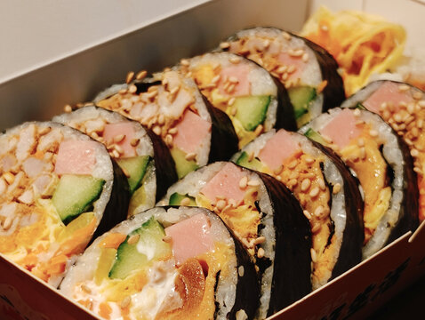 Assorted Sushi Rolls in a Takeout Box with Sesame Seeds