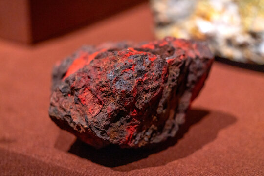 Rough Red Mineral Specimen with Dark Textured Surface on Red Background