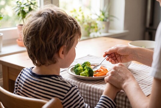 Parent assisting child during mealtime at the kitchen table