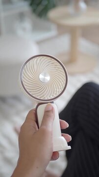 Woman hand holding portable handheld electric mini fan for cooling on hot summer day