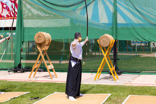 Traditionelles japanisches Bogenschie&szlig;en Kyudo, Bogensch&uuml;tze im Hakama visiert das Strohziel bei einer Vorf&uuml;hrung an