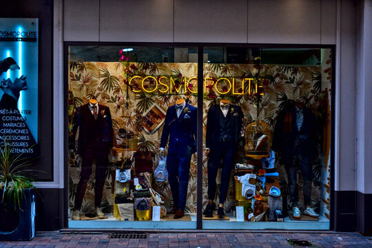 Editorial photo of the storefront and exotic window display of "Cosmopolite" men's suit boutique in Le Puy-en-Velay, France. Sept 20, 2024. Fashion, retail, and commerce illustration.