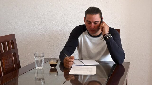 Stressed man discussing a contract over the phone at home