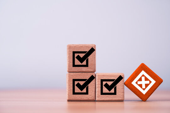 Checklist with check marks and red cross on wooden blocks symbolizes error detection, quality control, audit compliance, risk assessment, problem identification and corrective action in business.