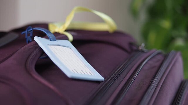 Close up of purple luggage suitcase with identification tag and travel accessories at home before departure