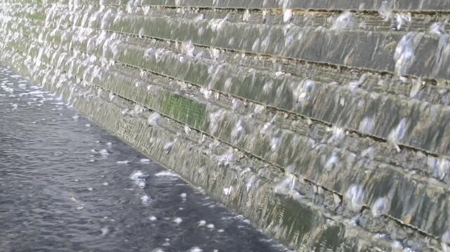 Close up of water feature steps with running liquid and splash ripples.