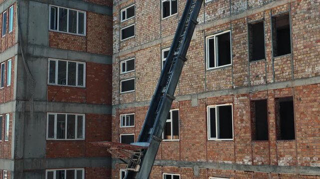 Construction ladder hoist descending along brick building facade