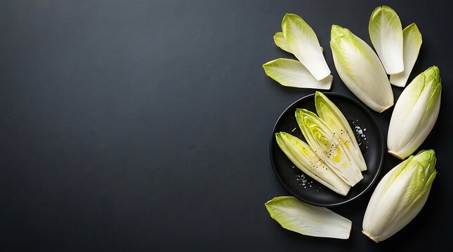 Fresh endive leaves arranged in a dark bowl for culinary presentation with minimalist background