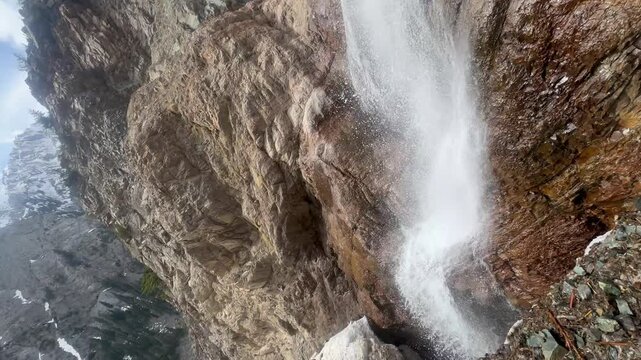 A high-action, close-up view of powerful water spray blasting off a rugged rocky ledge at a mountain waterfall in Khyber Pakhtunkhwa, Pakistan, September
