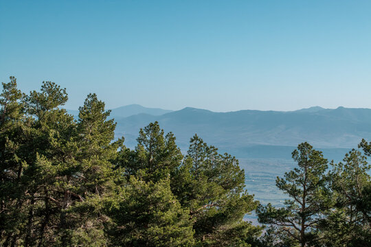 Valle del r&iacute;o Lozoya visto desde lo alto de la Sierra de Guadarrama, Madrid, Espa&ntilde;a. Valle visto sobre las copas de los pinos desde el camino en el junto al arroyo el Reajo Bajo en San Mames . 2020.