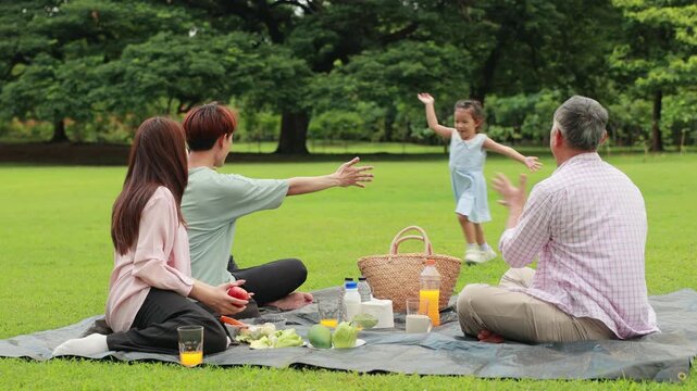 Slow motion hugging Happy father and daughter, Happy Asian family having fun time on picnic at city nature park sunny day, outdoor activitie with daughter father, mother and grandfather