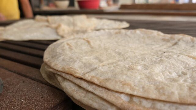 Stack of fresh flatbreads warming on a rustic wooden surface.