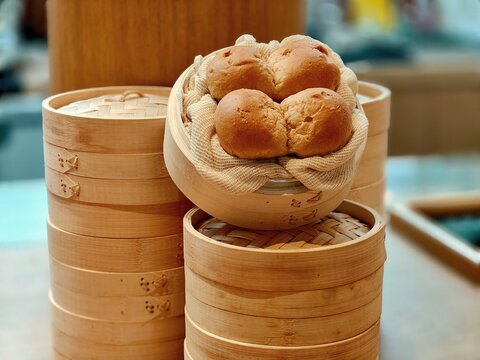 Artificial bread rolls displayed in bamboo steamers in a close-up view, showcasing decorative food props and restaurant display elements with warm tones and selective focus.