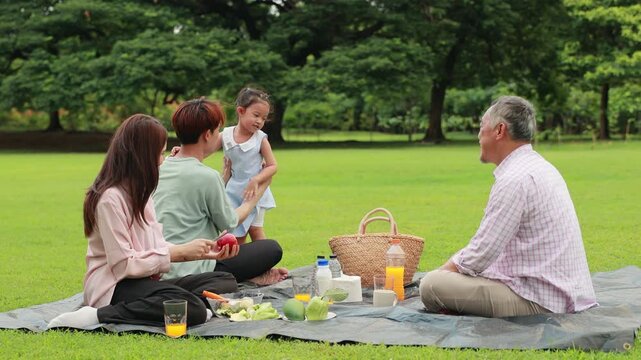 Slow motion hugging Happy father and daughter, Happy Asian family having fun time on picnic at city nature park sunny day, outdoor activitie with daughter father, mother and grandfather