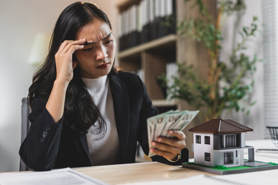 Stressed woman counting money for real estate investment.