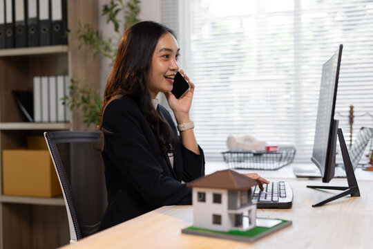 Asian businesswoman talking on phone working online. The real estate agent is on the phone while working in the office.