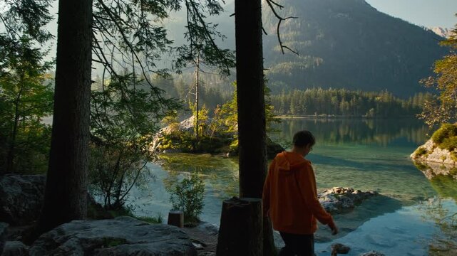 Young man walking at an idyllic lake in the Alps and enjoying the amazing view of the gorgeous landscape