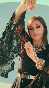 close-up hand waving dansing. happy woman Fashion model posing in desert. Long black dress hair flying wind slow motion. sexy beauty girl. Gold jewelry set necklace luxury life glamorous arab lady.