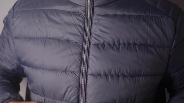 Man zipping up his black puffer jacket, medium shot of a man zipping up jacket.